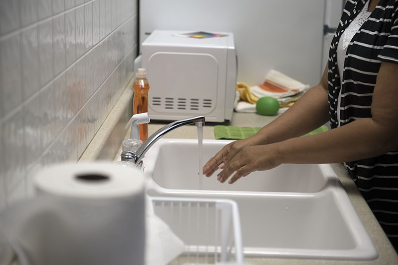 A woman washing her hands with soap and water at a sink.