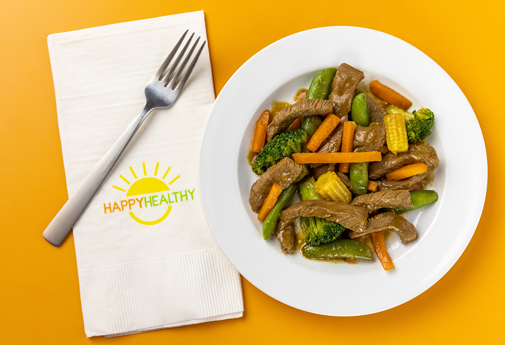 Beef Stir Fry in white bowl next to HappyHealthy napkin and fork