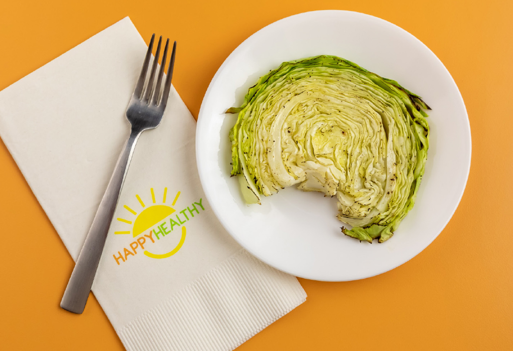 Cabbage steak on white plate next to HappyHealthy napkin and fork