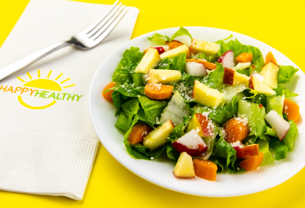 Chopped salad next to white HappyHealthy napkin with fork. 