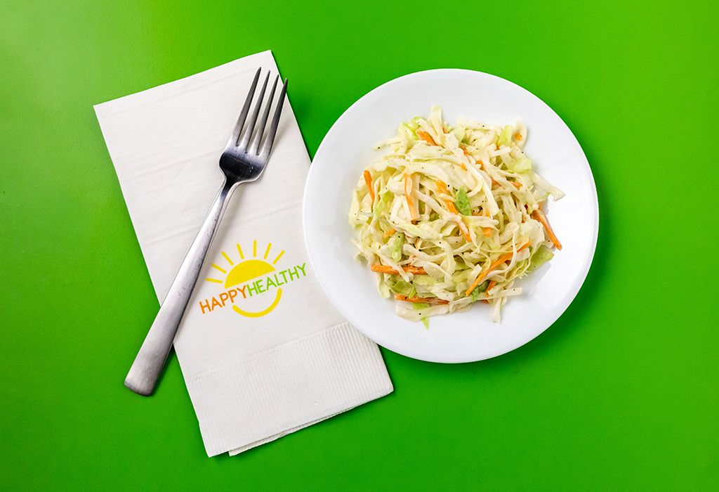 Coleslaw on a white plate with HappyHealthy napkin and fork to the left side.