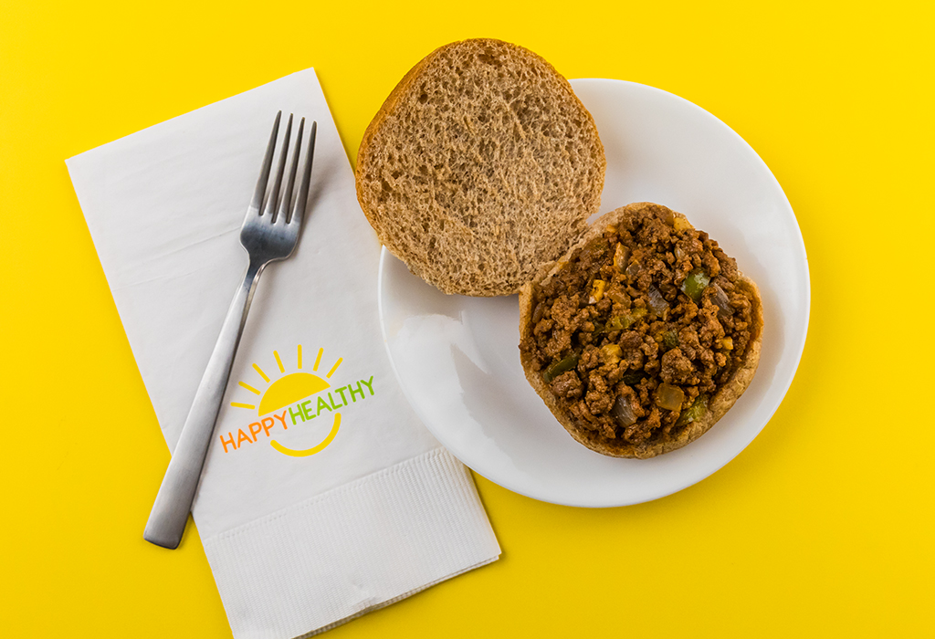 Easy Sloppy Joes (with bun) on a plate with a fork on a HappyHealthy napkin.