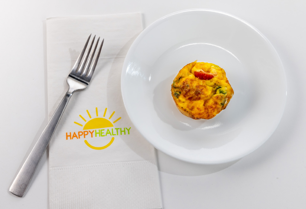 A plate with an egg muffin next to a fork with a HappyHealthy napkin
