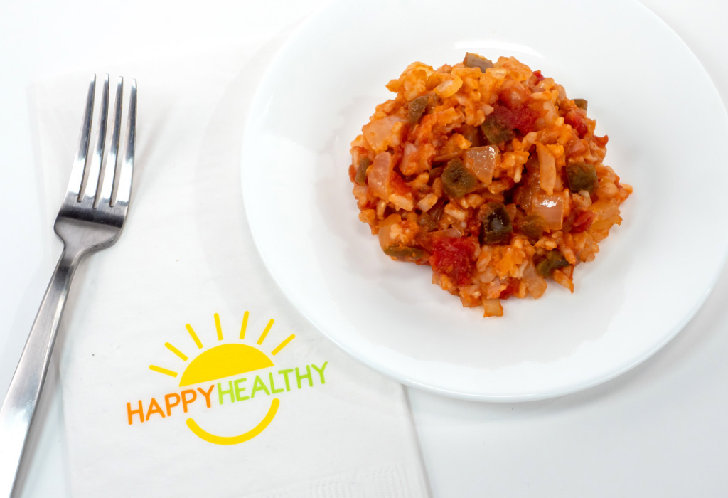 A white plate with fiesta rice next to a fork and HappyHealthy napkin