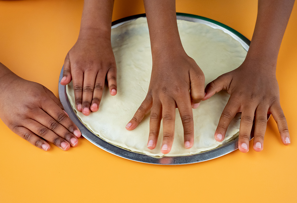 Kids forming pizza dough to a pan