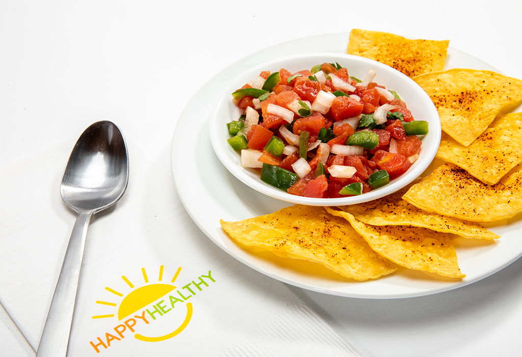 Homemade Tomato Salsa on in white bowl on white plate with tortilla chips, next to HappyHealthy napkin with spoon