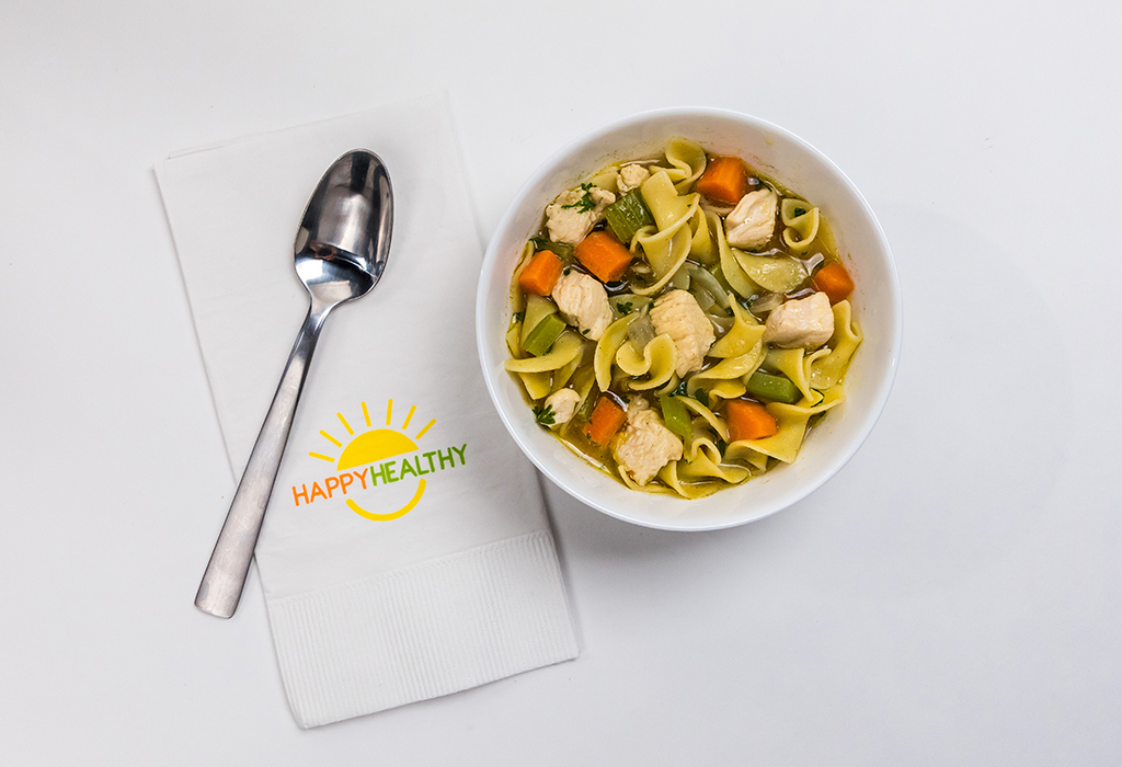 Bowl of soup with a spoon on a HappyHealthy napkin.