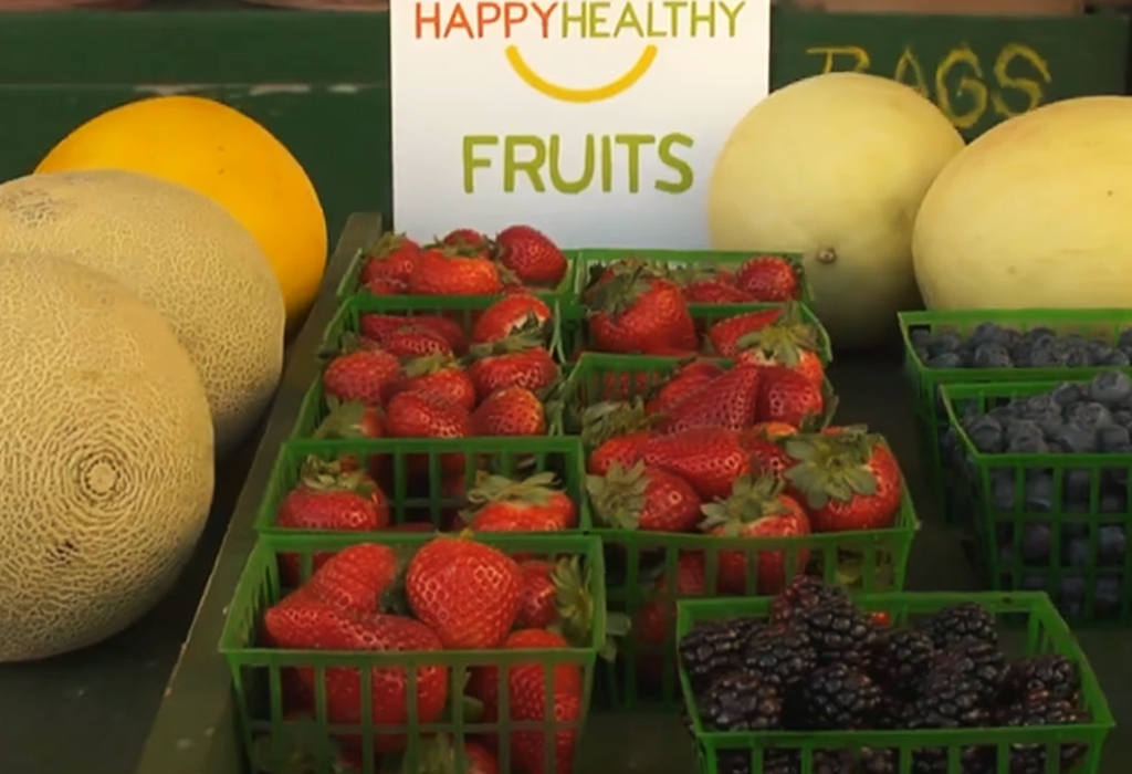 Fresh fruits in front of a Happy Healthy Fruits sign