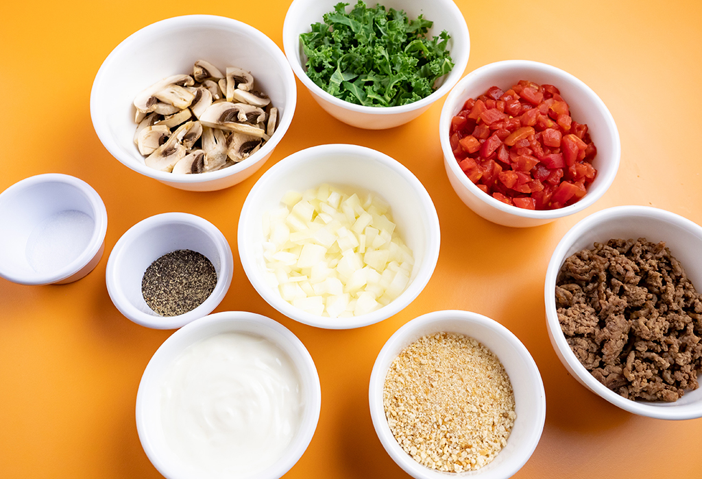 Various measured ingredients in white bowls to be used in a casserole