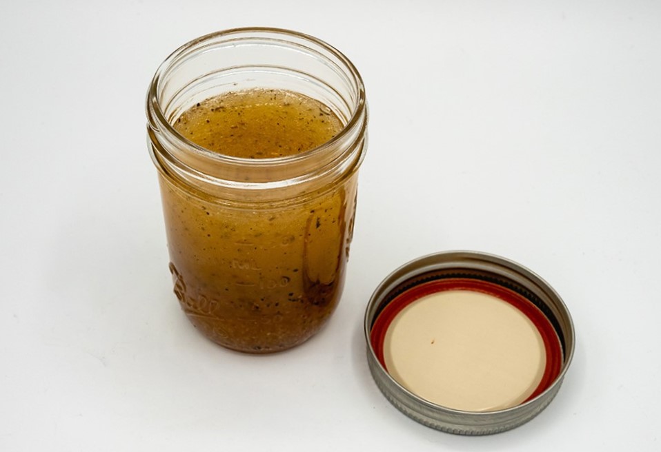 italian dressing in a glass jar with lid to the right.