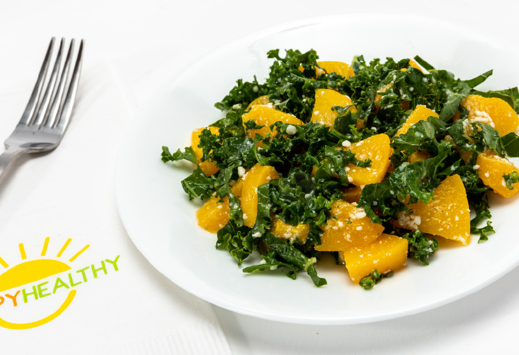 Kale salad on white plate next to HappyHealthy napkin and fork