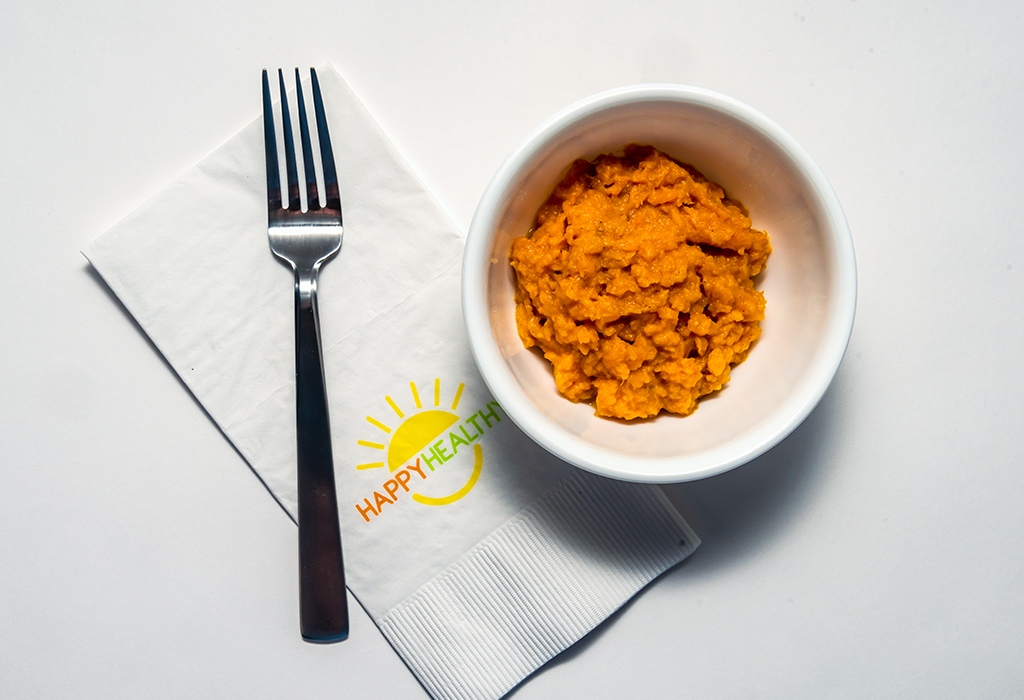 Bowl of mashed sweet potatoes with fork on HappyHealthy napkin.