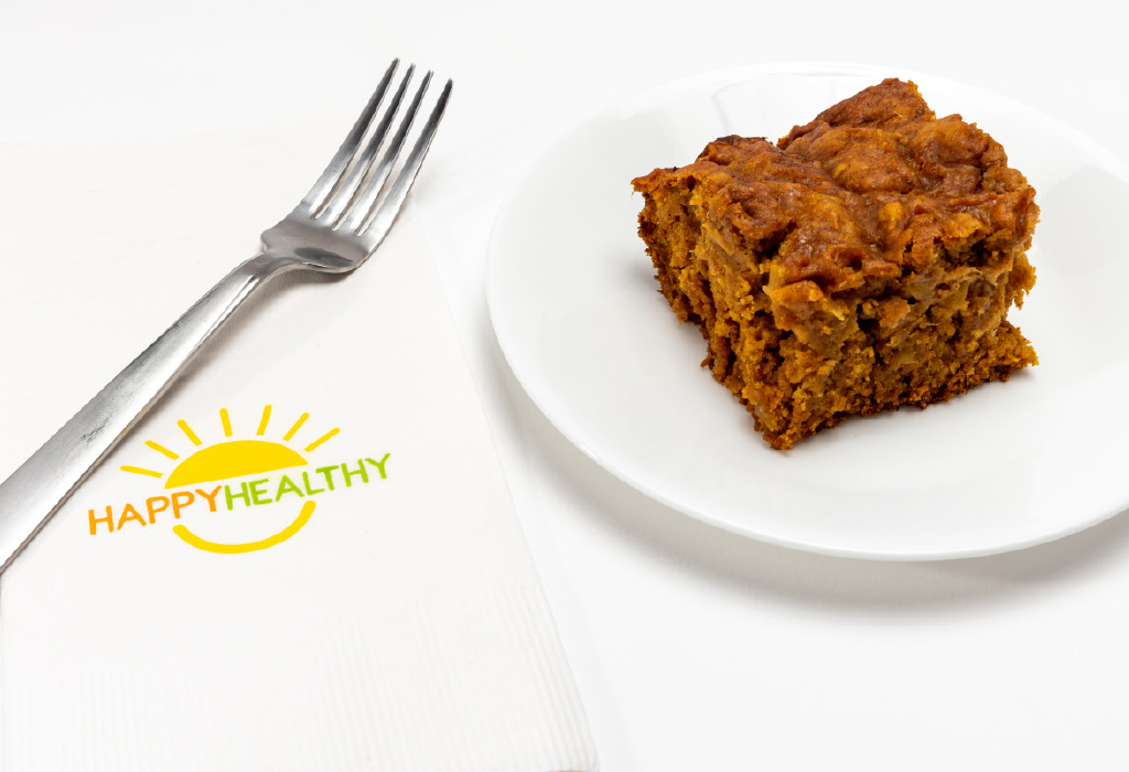 A pineapple pumpkin square on a white plate next two a fork and Happy Healthy napkin