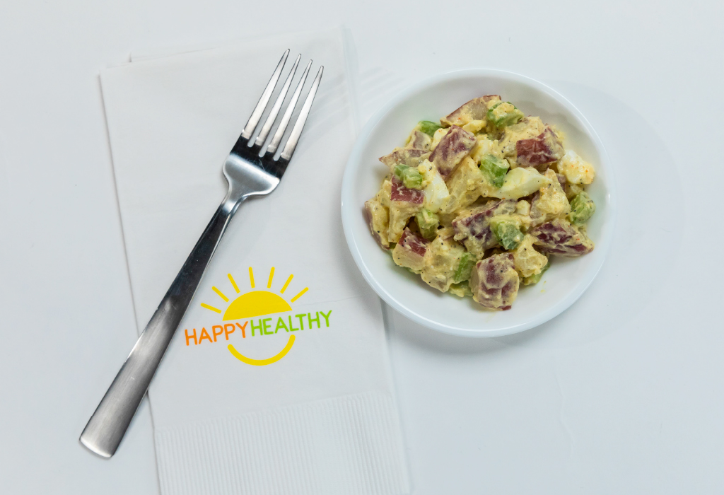 Plate with potato salad beside a napkin and fork. beside a napkin and fork.