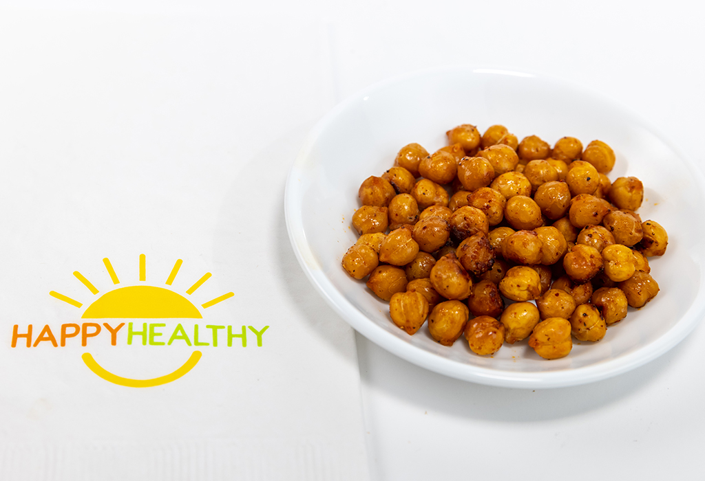 A white plate with roasted chick peas next to a Happy Healthy napkin