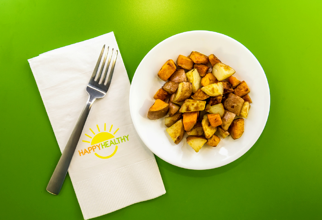 A plate of cubed and roasted potatoes with a HappyHealthy napkin and fork to the side.