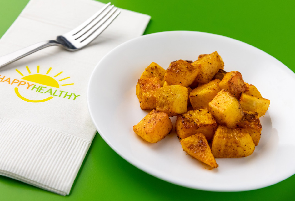 Roasted Turnips on white plate next to white HappyHealthy napkin and fork