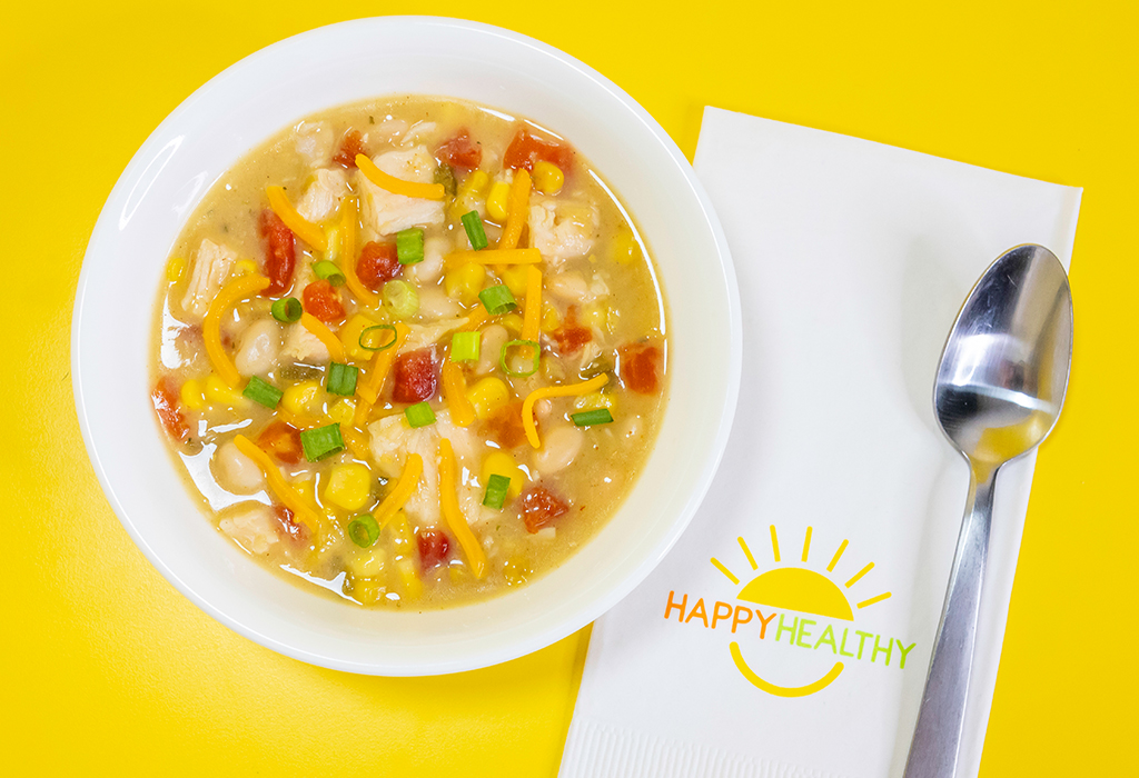 A bowl of southwestern chicken chili next to a white napkin and spoon