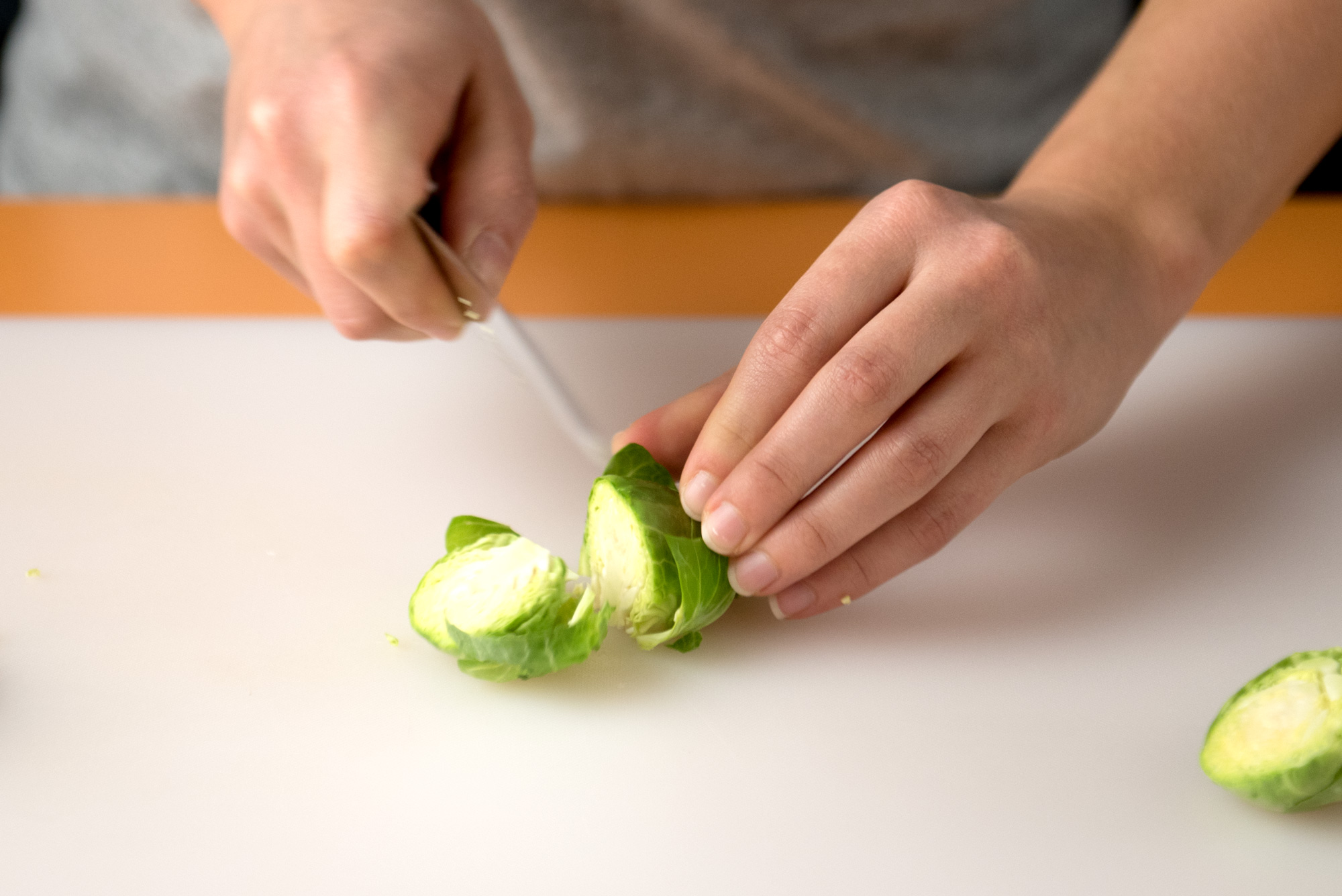 A woman cutting brussels sprouts.