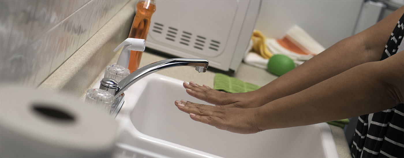 A woman displaying her hands at a sink.