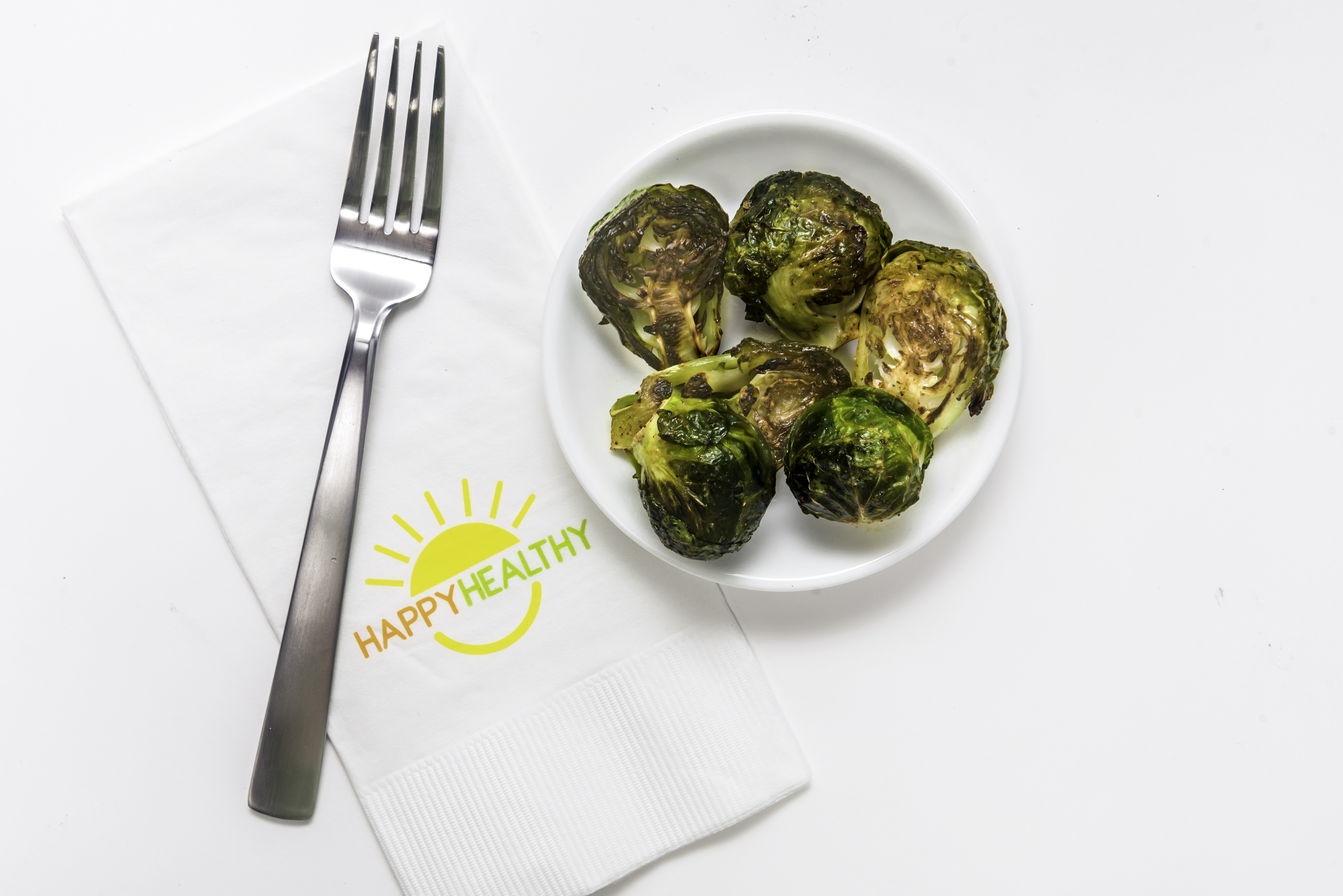 Bowl of roasted brussels sprouts beside napkin and fork