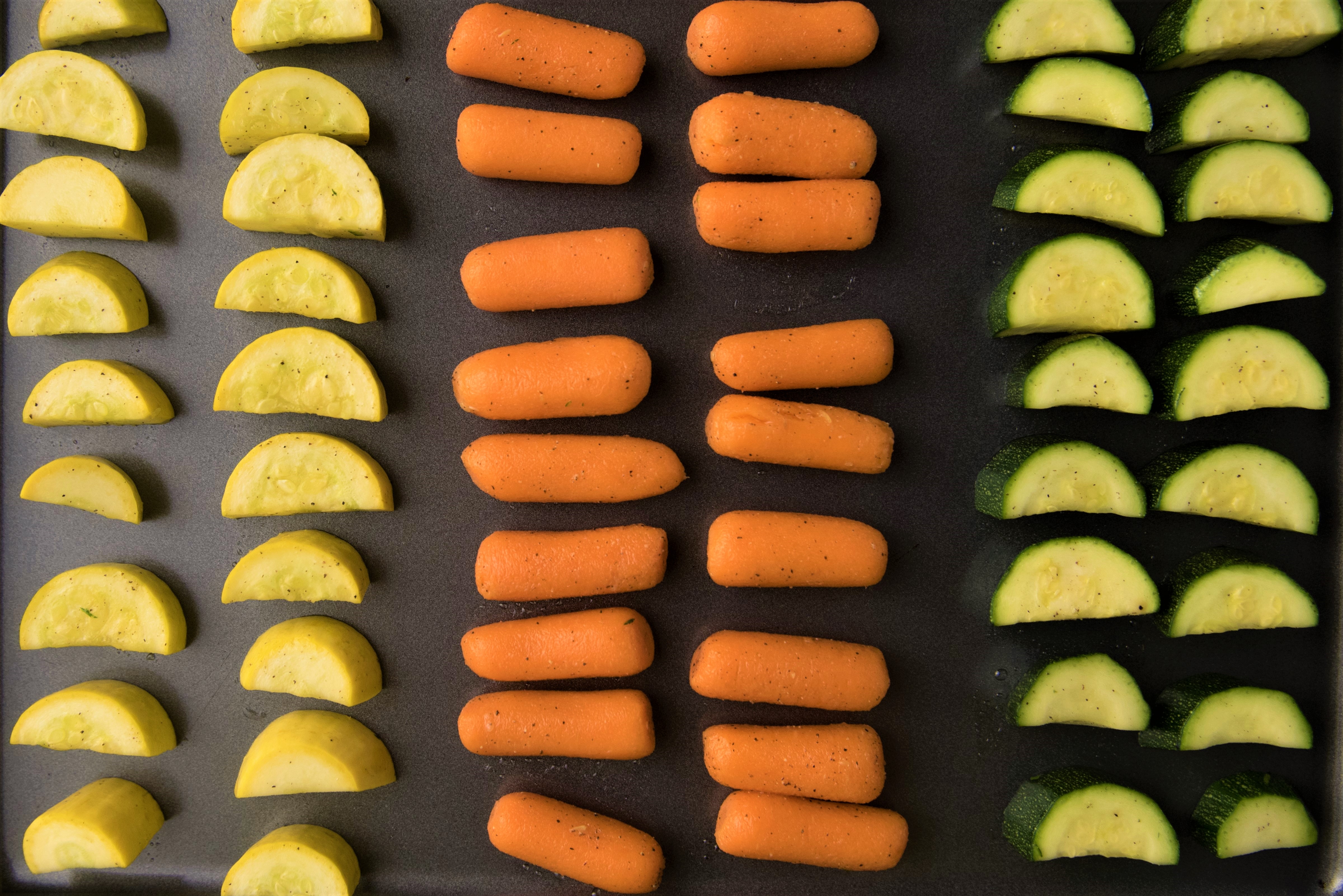 Yellow squash, carrots, and zucchini on baking sheet to be roasted.