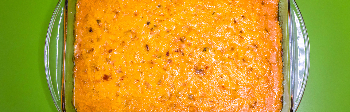 A casserole dish of Fiesta Cheesy Chicken on a green background
