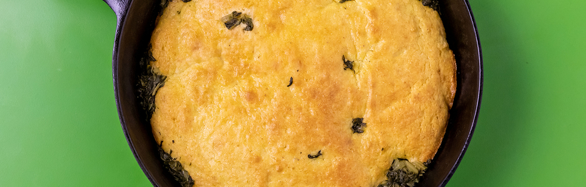 A frying pan with baked green and cornbread