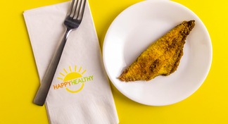 Fork and napkin beside plate with a cooked, seasoned catfish fillet