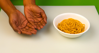 two open hands palm up beside a bowl of spaghetti noodles