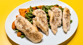 4 seasoned chicken filets over green beans and sweet potatoes on plate