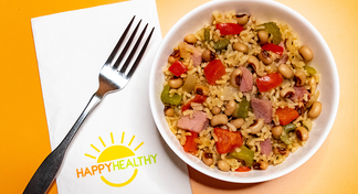 A white bowl filled with black eyed peas and rice next to a fork and HappyHealthy napkin