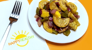 A white plate of foil packet roasted vegetables next to a happy healthy napkin and fork