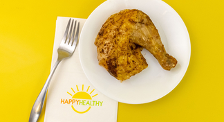 A chicken thigh on a white plate next to a Happy Healthy napkin and fork