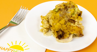 A white plate with Slow Cooker Chicken and Dressing next to a fork and HappyHealthy napkin