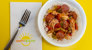 a white bowl with jambalaya and rice next to a fork and Happy Healthy Napkin