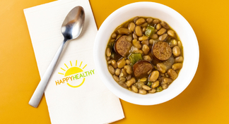 A bowl of slow cooker pinto beans next to a spoon and HappyHealthy napkin