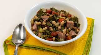 A bowl of Slow Cooker Sausage, Greens, and Black-eyed Peas on a yellow napkin