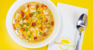 A bowl of southwestern chicken chili next to a white napkin and spoon