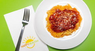 A white plate of Spaghetti Squash with Tomato Sauce next to a fork and HappyHealthy napkin