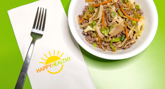 A white bowl filled with spring roll in a bowl next to a fork and Happy Healthy napkin