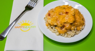 A white plate of Fiesta Cheesy Chicken on a green background next to a fork