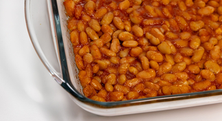 A casserole dish of baked beans on a white background