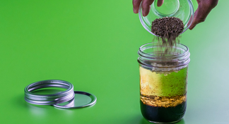 Hand pouring contents of bowl into a jar to make salad dressing
