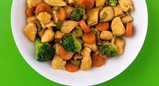 Chicken stir fry dish with sauteed carrots, broccoli, celery and chicken in a white bow