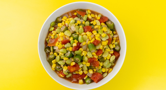 A bowl of Corn, Lima Beans, Okra, and Tomatoes on a yellow background