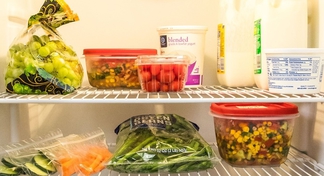 various fruits and vegetables in plastic bags and containers on refrigerator shelves