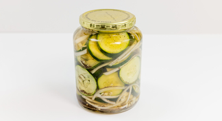 A pickle jar full of Quick-Pickle Cucumbers and Onions on a white background