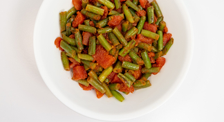 A white bowl of Sautéed Green Beans on a white background
