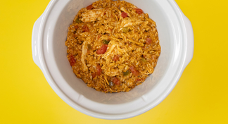 A white slow cooker full of taco chicken and rice on a yellow background